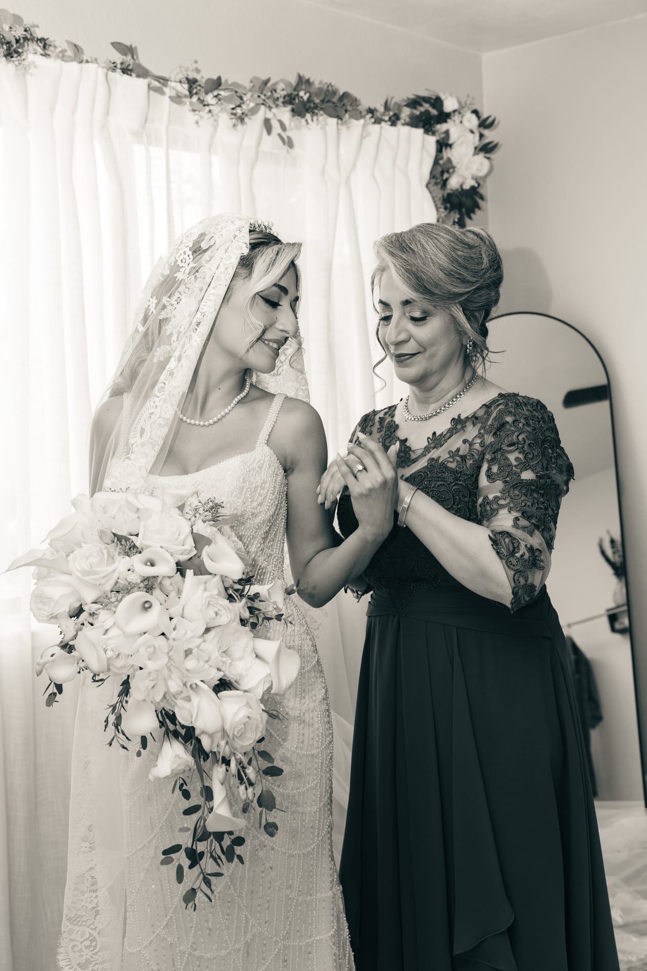 Bride and her mother holding hands before the ceremony, black and white