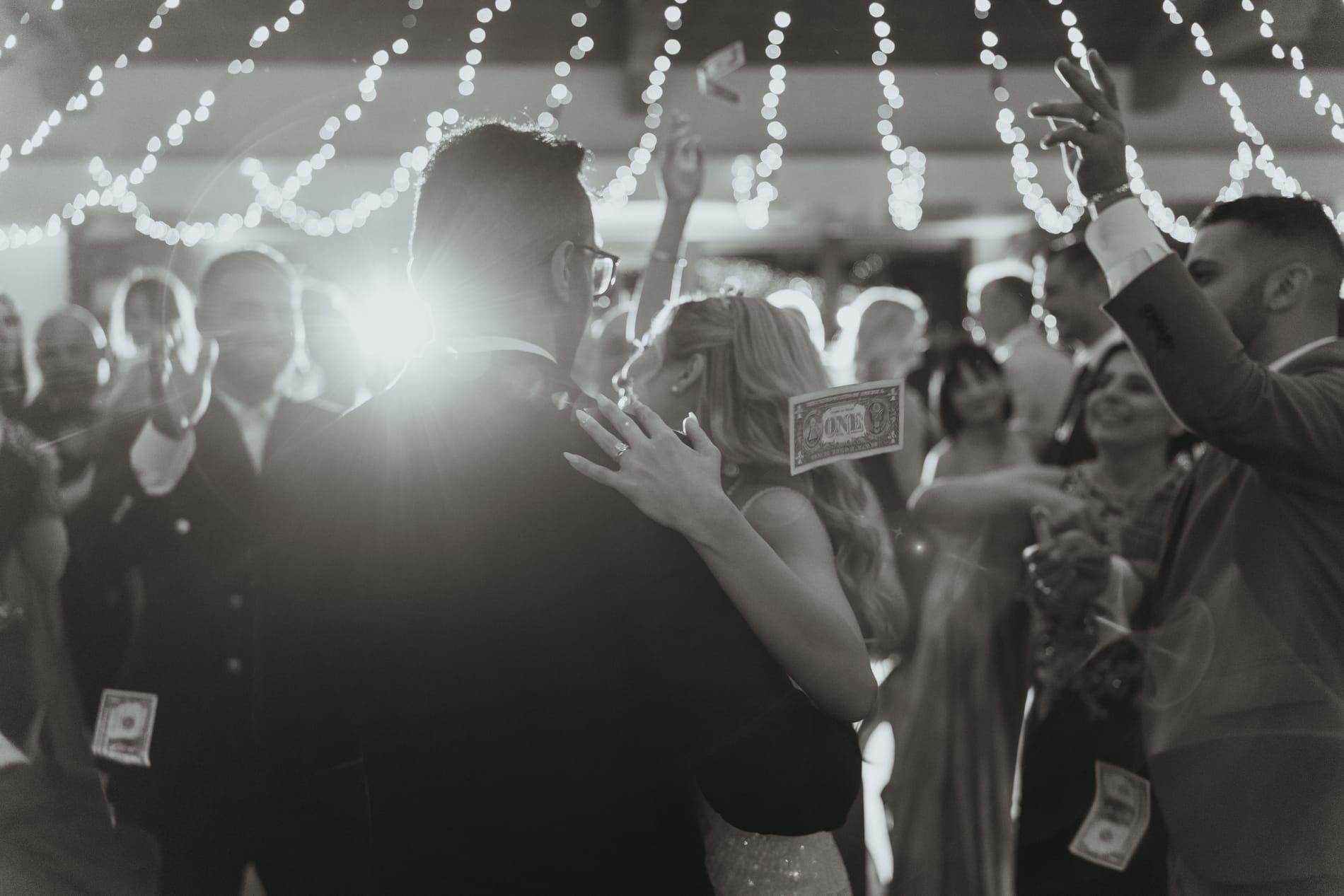 The money dance, guests pressing in with bills raised, black and white